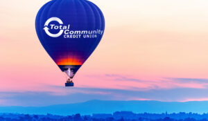 hot air balloon with TCCU logo floats over landscape