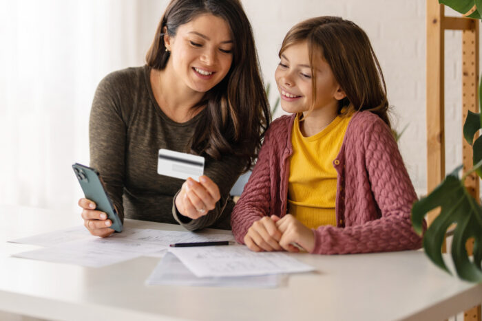 mother teaching daughter about debit card use
