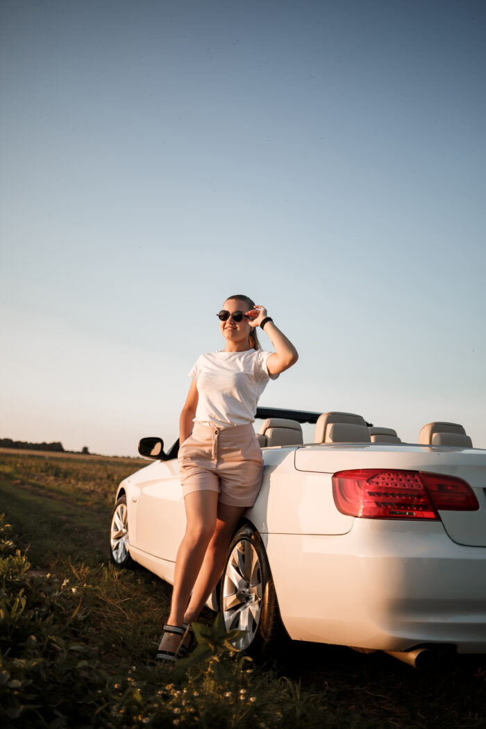 woman in sunshine admires her new car