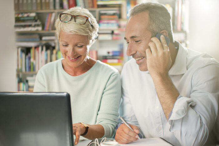 happy mature couple at home making plans using online tools