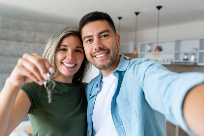 Young couple, new homeowners, shows keys to their new home
