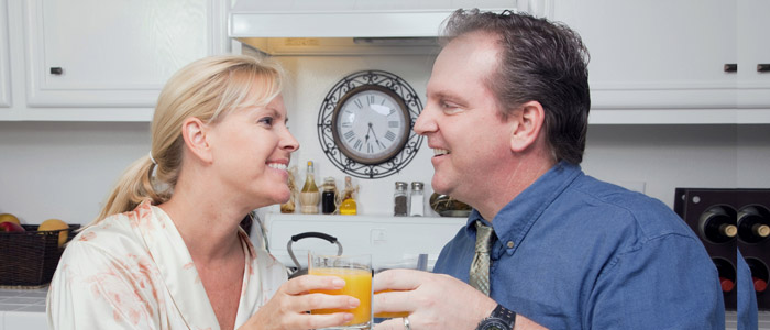 Happy Woman and Man In Kitchen enjoying Breakfast.